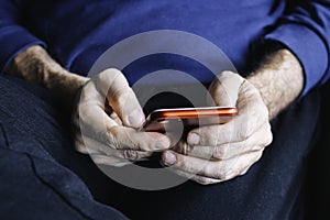 Male hands holding a mobile phone in a waiting roomTechnology concept. Man hands with smartphone