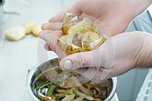 Male hands holding potato peels over bowl of vegetable peelings closeup. Separate waste collection, waste free.