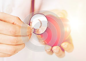 Male hands holding red heart and stethoscope