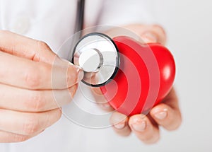 Male hands holding red heart and stethoscope