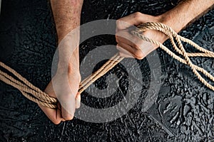 Male hands holding a rope on a black background