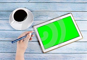 Male hands holding tablet pc with green empty screen on wooden background