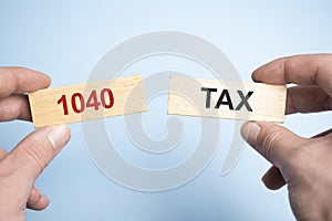 Male hands holding two wooden pegs with TAX 1040 sign