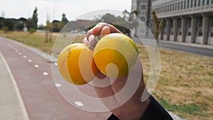 Male hands holding two yellow lemons background of a City Street road
