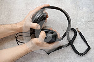 Male hands holding vintage stereo headphones against a gray background