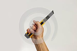 Male hands holding yellow sharp box cutter. Isolated on gray background. Closeup
