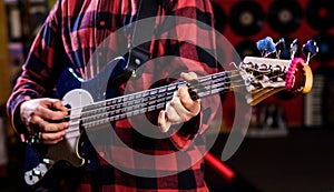 Male hands holds bass guitar, play music in club atmosphere background. Play guitar concept. Musician, artist play