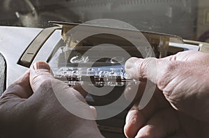 Male hands insert a no name cassette into an old audio system