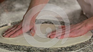 Male hands kneading dough in flour on a table