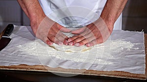 Male hands kneading dough in flour on a table