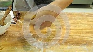 Male hands kneading dough in flour on table and and take it away