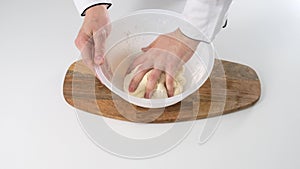 Male hands kneading dough in flour on a table and wooden board. Close up.