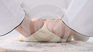 Male hands kneading dough in flour on a table and wooden board. Close up.