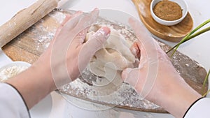 Male hands kneading dough in flour on a table and wooden board. Close up.