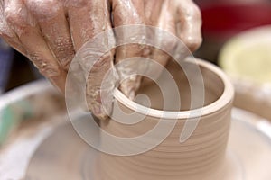 male hands making ceramic cup on pottery wheel