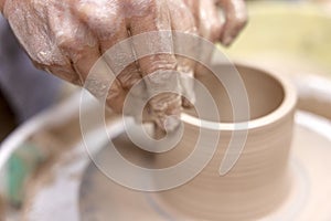 male hands making ceramic cup on pottery wheel