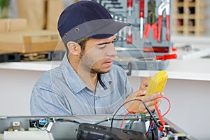 Male hands measuring voltage in electrical wall recepticle