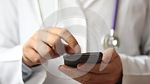 Male hands of medicalc doctor typing SMS message on smart phone.
