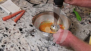 Male hands mix a salad dressing recipe with an immersion blender