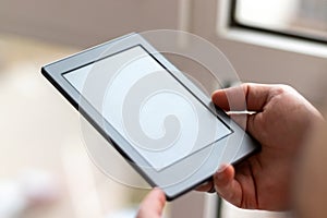 Male hands with modern e-book with blank screen closeup. Reading at home on the balcony with a pocket reader