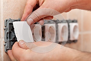 Male hands mounting electrical wall socket - closeup