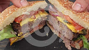 Male hands are opening fresh homemade grilled burger cut in two halves