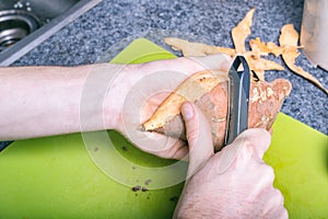 Male hands peeling sweet potatoes