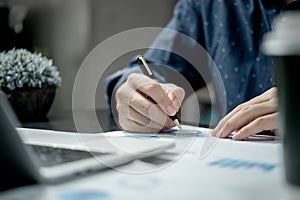 Male hands with pen over document graph and chart on desk