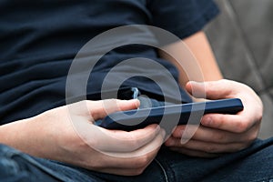 Male hands play videogames on smartphone closeup. Guy using mobile phone to play game or watch online video content.