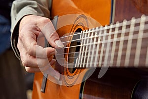 Male hands playing acoustic guitar, close up.  Teacher is giving guitar lesson