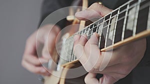 Male hands playing on electric guitar close up. Fingers on guitar fretboard holding pick and playing chords and solo. Musical inst