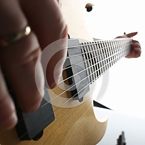 Male hands playing electric guitar on maple fretboard