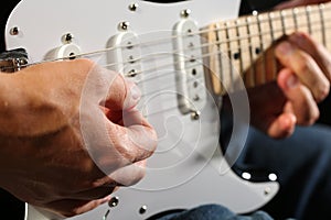 Male hands playing electric guitar with plectrum closeup