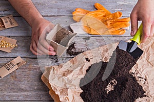 Male hands are potting using trowel.