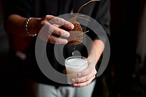 Male hands pour in glasse vegan coconut milk