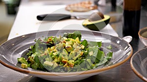 Male hands pouring souce and seasoning avocado salad