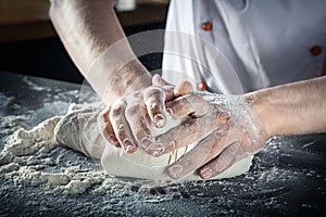 Male hands preparing pizza dough. chef in kitchen prepares the dough for gluten free pasta or bakery. baker kneads dough on the