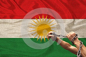 Male hands of a prisoner in iron chains against the background of the national flag of kurdistan, rojava, concept of political