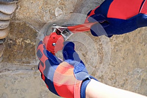 Male hands in protective gloves repairing tap using special wrench