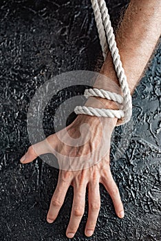 Male hands are pulling the rope on a black background