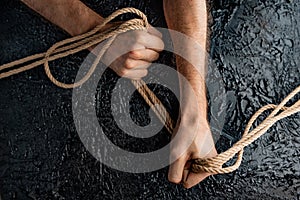 Male hands are pulling the rope on a black background