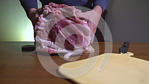 Male hands put a large piece of meat on a cutting board, home cooking. A man prepares to butcher and cook meat