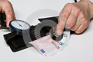 Male hands put a stethoscope to cash-box with euro money