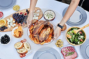 Male Hands Putting Roasted Chicken on Dinner Table photo