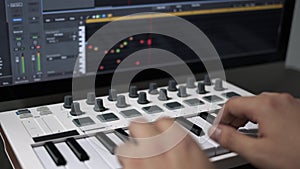 Male hands recording midi keyboard in sequencer in computer in home studio