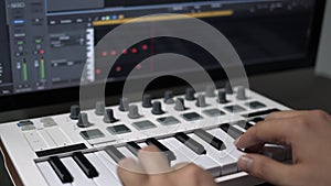 Male hands recording midi keyboard in sequencer in computer in home studio