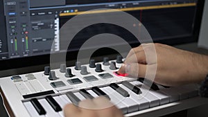 Male hands recording midi keyboard in sequencer in computer in home studio