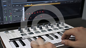 Male hands recording midi keyboard in sequencer in computer in home studio