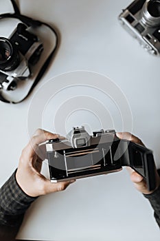 Male hands reloading film retro camera on a white table. vertical