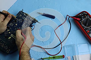 Male hands repair an electronic device using Multimetr, measuring the voltage of the computer motherboard with  digital multimeter